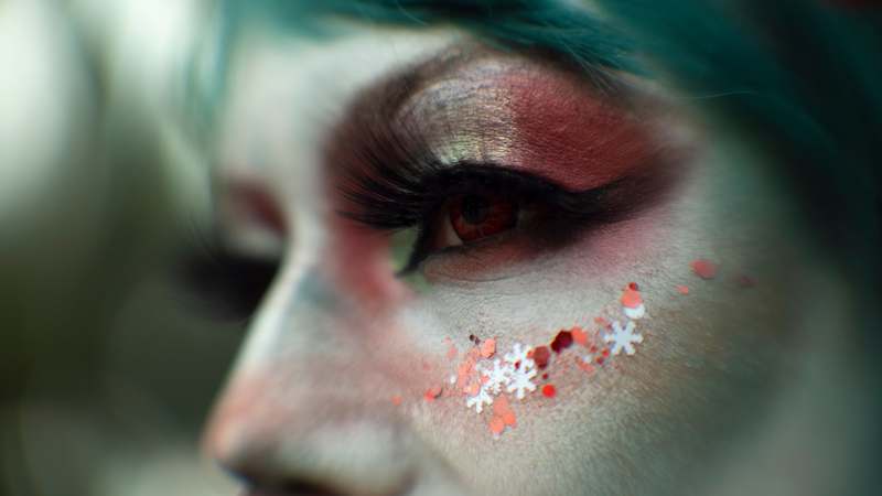 Close-up of a model wearing elaborate fantasy makeup with gemstones and shimmering pigments